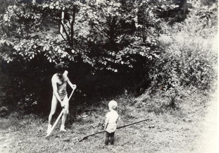 Father and child mowing grass