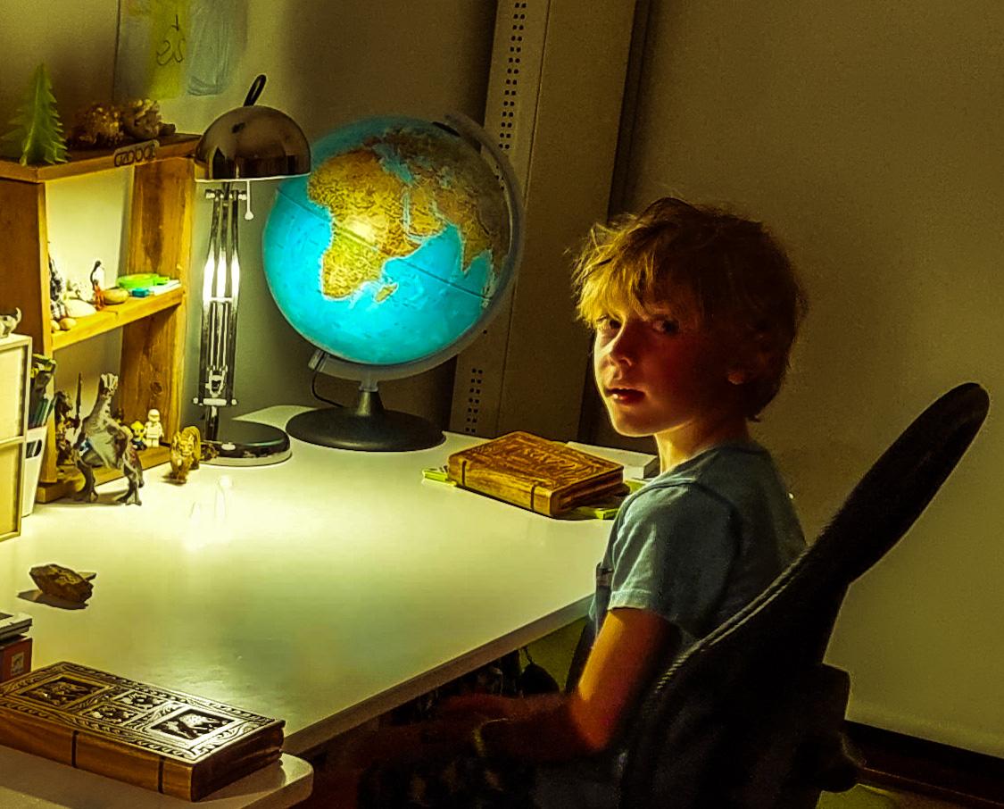 Small boy at a desk with a globe